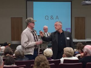 Moderators Phil Sutton (center) and Mike Hourhan (right) kept questions and answers to 2 minutes. They faced harsh criticism from the crowd over time limits.