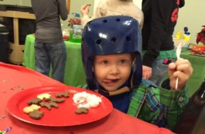 3-year old Keegan Gaddis licks his lips after eating refreshments. The helmet is to protect him from getting hurt when he falls.