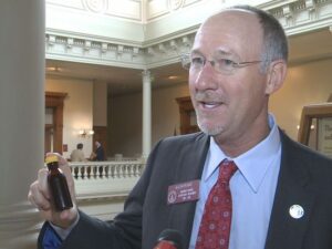 Rep. Allen Peake (R-Macon) is leading the charge to legalize cannabis oil in Georgia. Here he holds an empty bottle similar to those that might be used to hold the drug. (photo courtesy Elise Brown, WMAZ-TV)